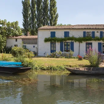 Barque et maison au bord d'un canal du Marais poitevin