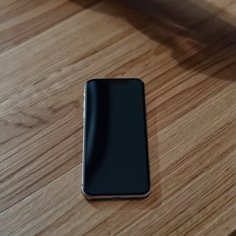 Telephone a l'ecran eteint pose seul sur une table en bois clair