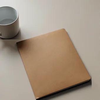 Chemise cartonnee kraft posee sur un bureau clair, a cote d'une tasse