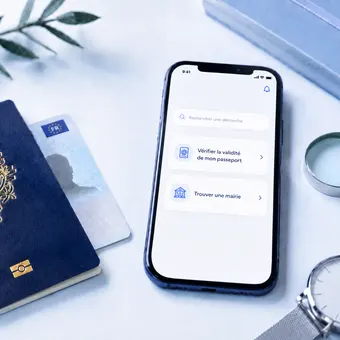 Smartphone affichant un outil de vérification, passeport posé à côté